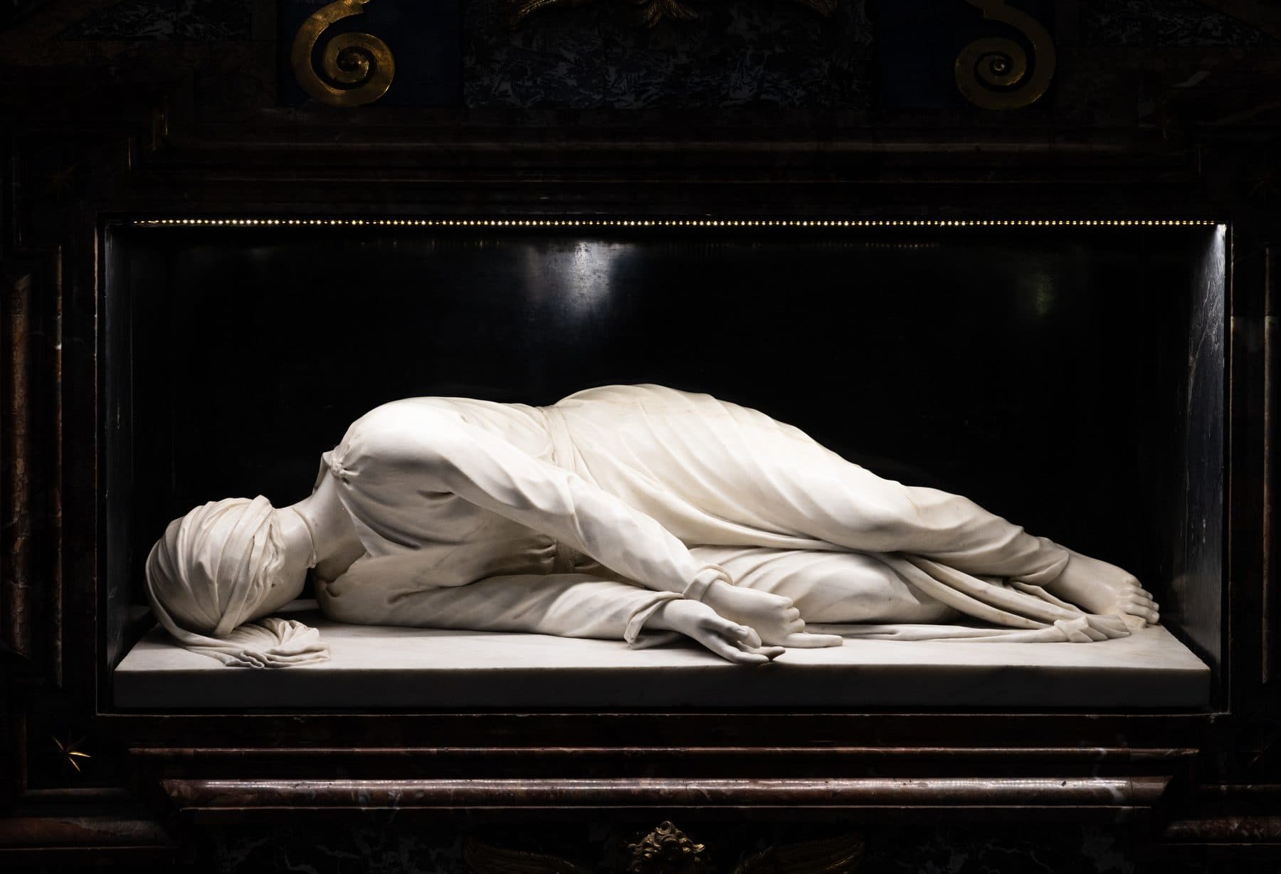 Stefano Maderno's 1600 white marble sculpture of St Cecilia lying on her side beneath the high altar of Santa Cecilia in Trastevere, Rome.