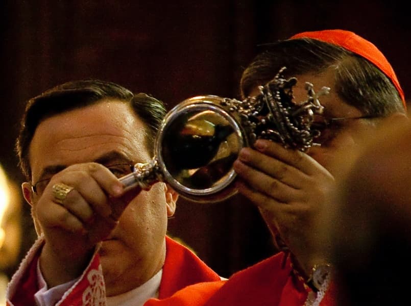 A cardinal in red vestments holds up a silver-and-crystal reliquary containing the ampoule of St Januarius's blood during the liquefaction ceremony in Naples Cathedral.
