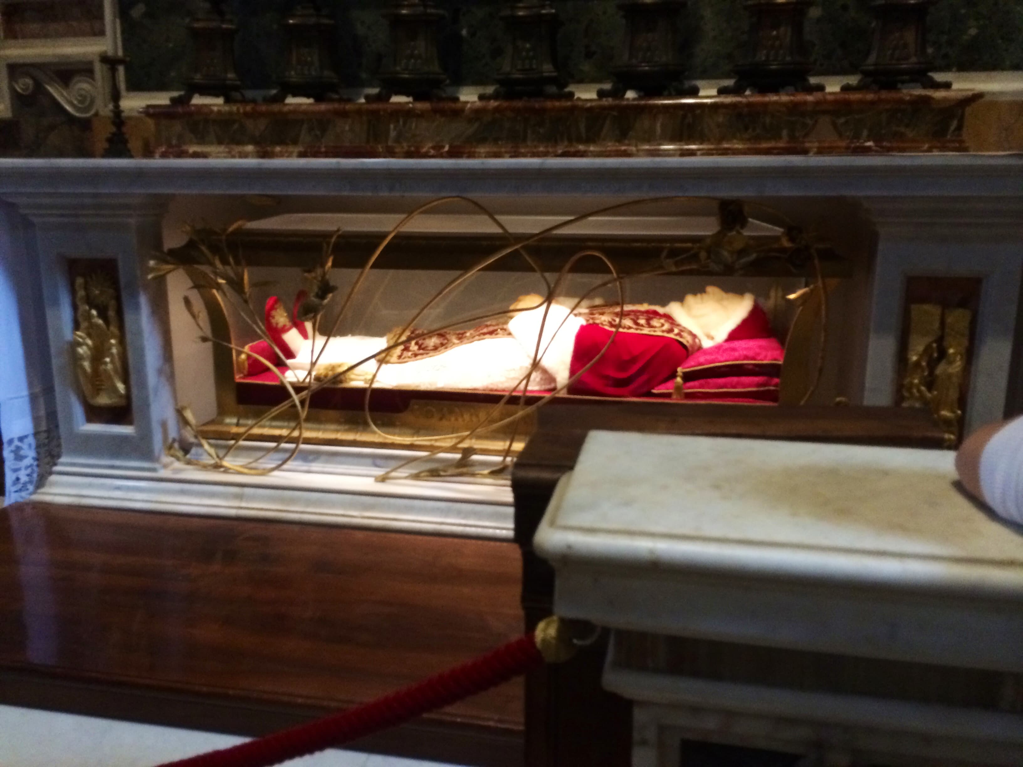 The embalmed body of Pope St John XXIII, vested in red, in a glass-fronted reliquary beneath the Altar of St Jerome in St Peter's Basilica.