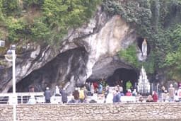 The grotto of Massabielle at Lourdes with candles, altar, and the statue of the Virgin in the rock niche